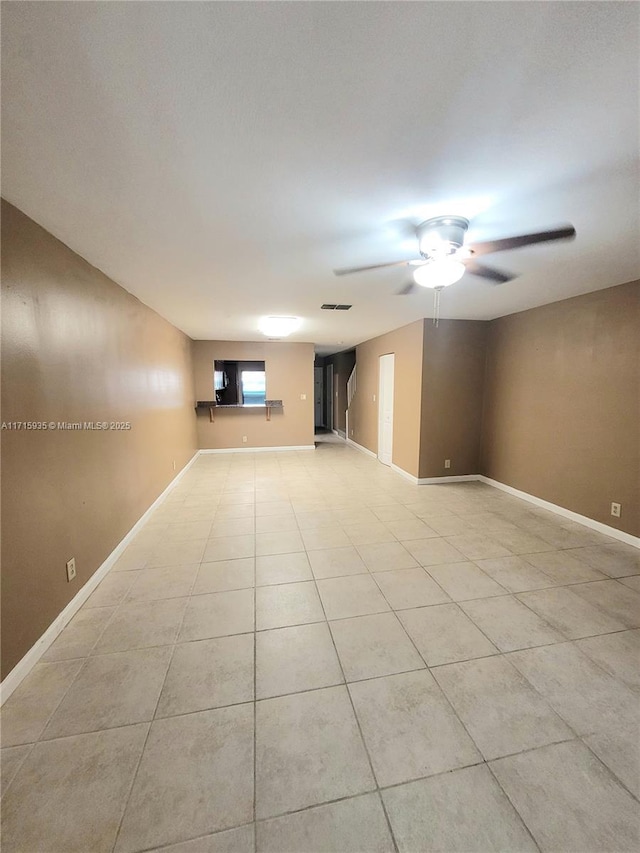 tiled empty room featuring ceiling fan