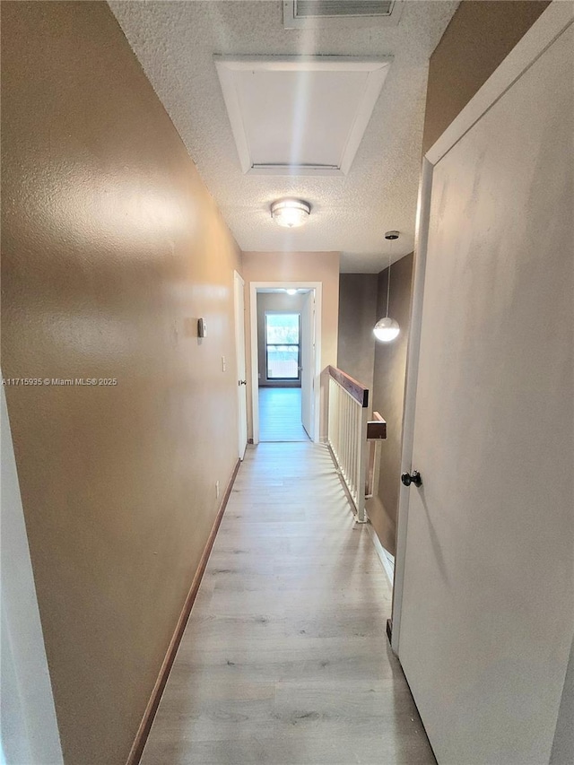 corridor with a textured ceiling and light wood-type flooring