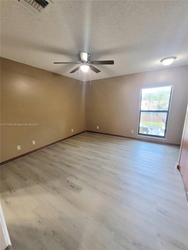 unfurnished room featuring ceiling fan, light wood-type flooring, and a textured ceiling