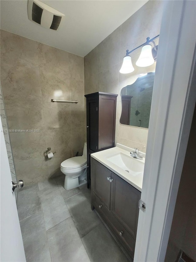 bathroom featuring vanity, toilet, and tile walls