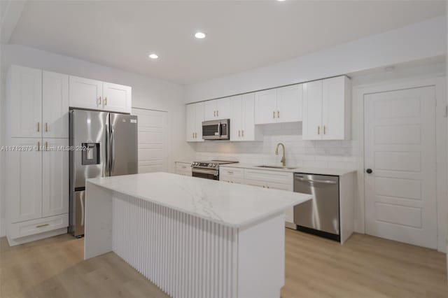 kitchen with a center island, sink, light hardwood / wood-style floors, white cabinetry, and stainless steel appliances