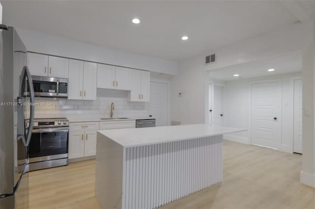 kitchen featuring a center island, white cabinets, sink, appliances with stainless steel finishes, and light hardwood / wood-style floors