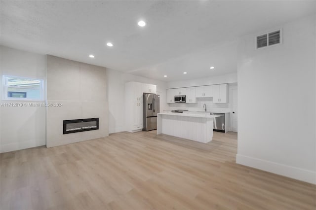 unfurnished living room featuring a large fireplace, light wood-type flooring, and sink