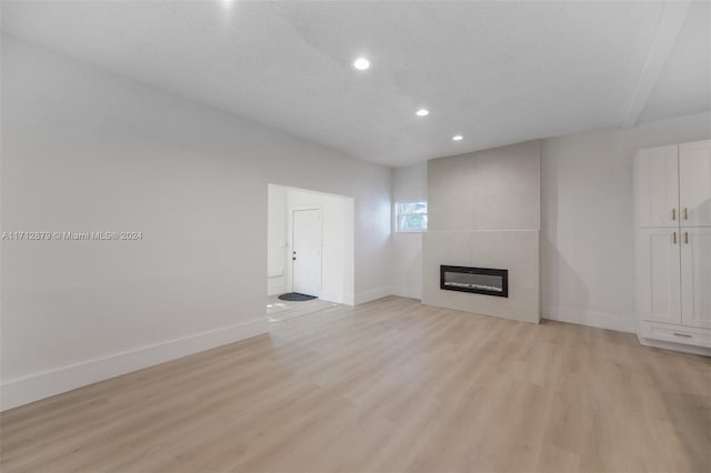 unfurnished living room featuring a fireplace, light hardwood / wood-style floors, and a textured ceiling