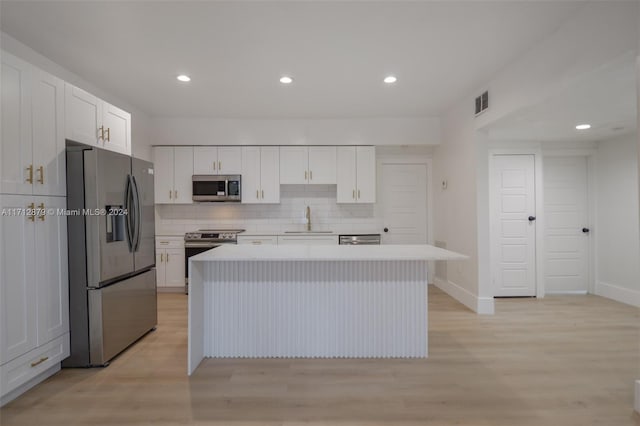 kitchen with sink, a center island, light hardwood / wood-style floors, white cabinets, and appliances with stainless steel finishes