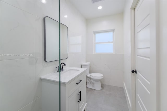 bathroom featuring vanity, tile walls, and toilet