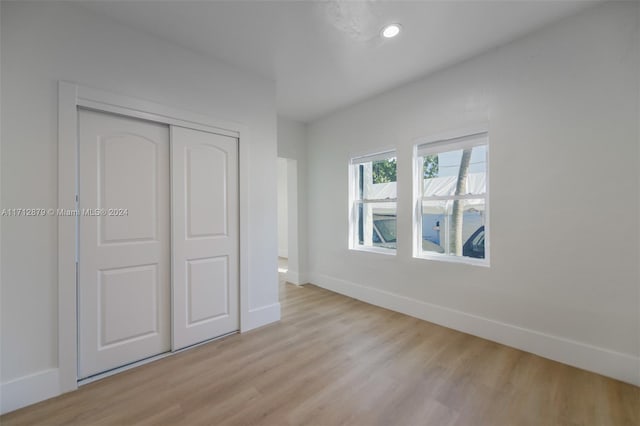 unfurnished bedroom with a closet and light wood-type flooring