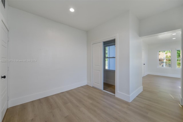 unfurnished bedroom featuring light wood-type flooring, multiple windows, and a closet