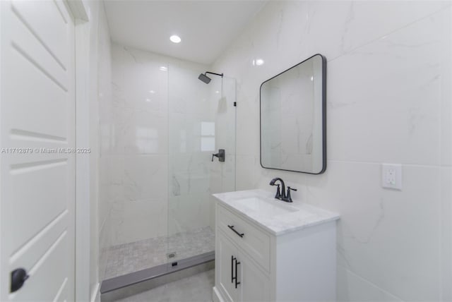 bathroom with vanity, tiled shower, and tile walls