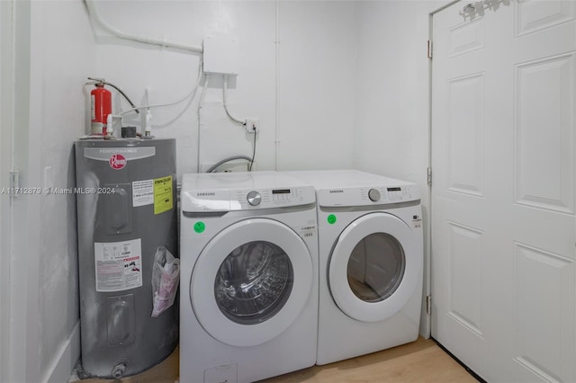 laundry area with washing machine and dryer, water heater, and light hardwood / wood-style floors