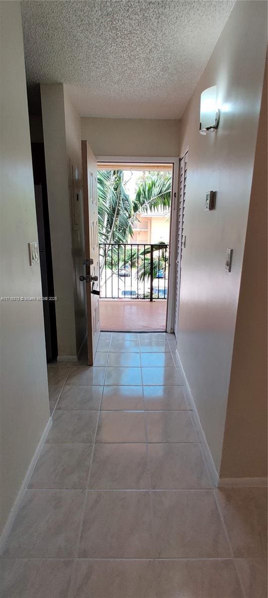 hallway featuring light tile patterned floors and a textured ceiling