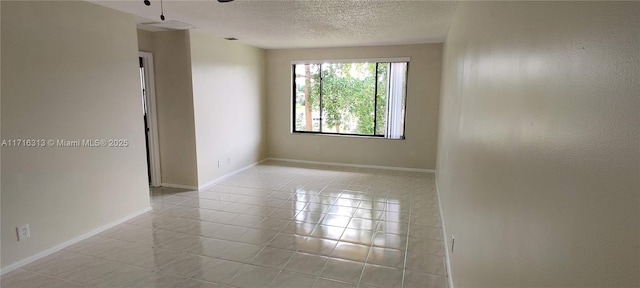 tiled empty room featuring ceiling fan and a textured ceiling