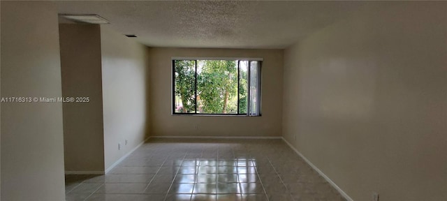 unfurnished room featuring tile patterned flooring and a textured ceiling