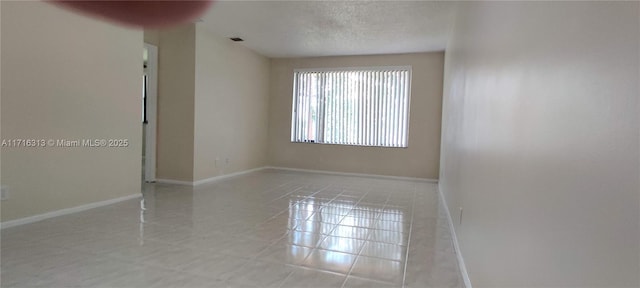 tiled empty room with a textured ceiling