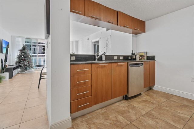 kitchen featuring sink, a textured ceiling, light tile patterned floors, and dishwasher