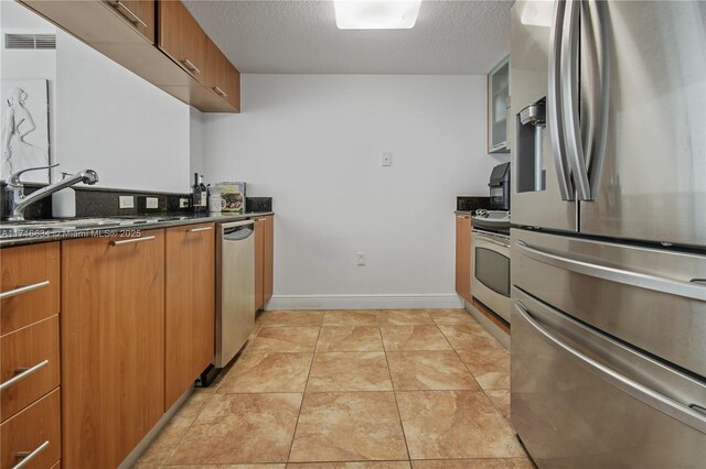 kitchen with light tile patterned floors, sink, a textured ceiling, and appliances with stainless steel finishes