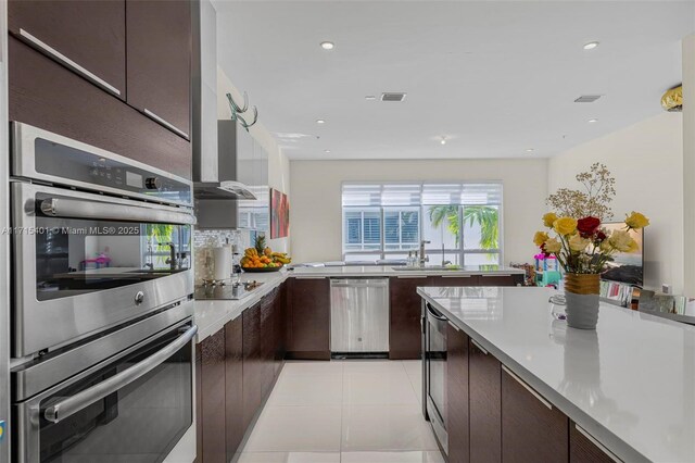 kitchen featuring dark brown cabinets, light tile patterned floors, stainless steel appliances, and sink