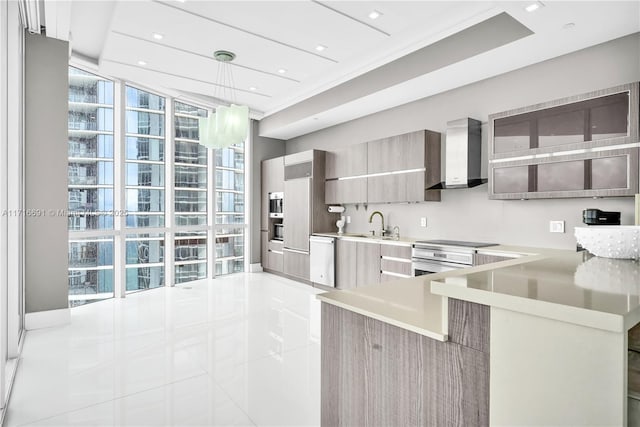 kitchen with kitchen peninsula, stainless steel dishwasher, wall chimney exhaust hood, decorative light fixtures, and light tile patterned flooring