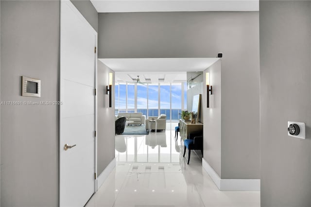 corridor with floor to ceiling windows and light tile patterned floors