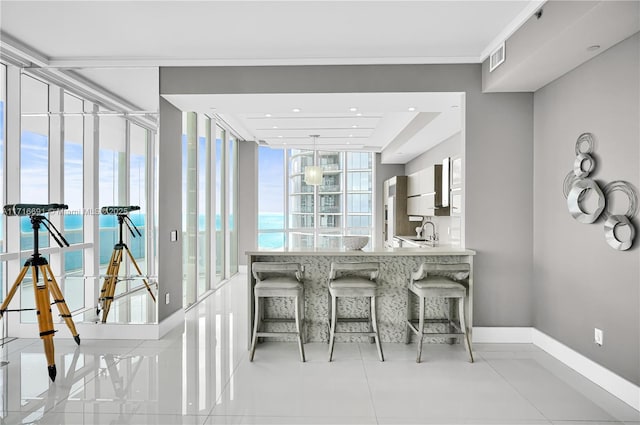 bar featuring floor to ceiling windows, a water view, light tile patterned floors, and sink