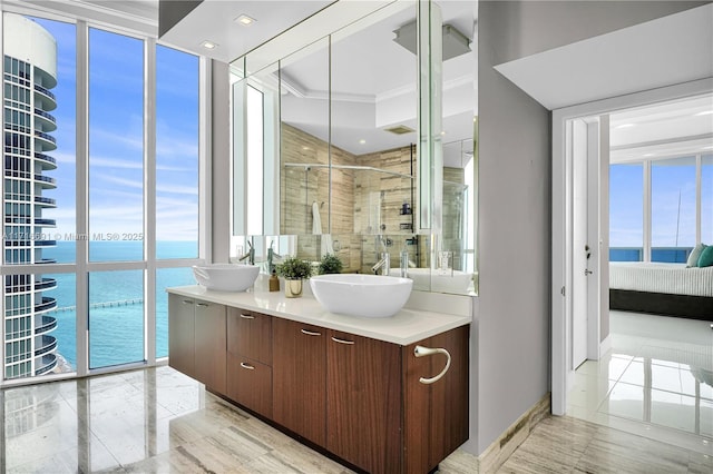 bathroom with a wealth of natural light, a water view, a shower with shower door, and a wall of windows