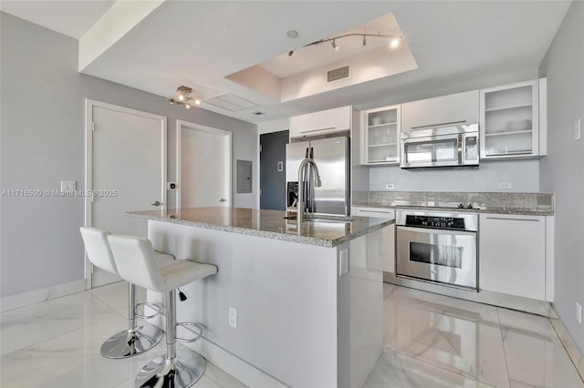 888 Biscayne Blvd Unit 411, Miami, FL 33132 - kitchen with appliances with stainless steel finishes, light marble finish floors, white cabinets, a center island with sink, and a tray ceiling