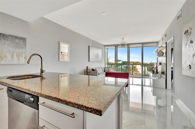 kitchen featuring expansive windows, sink, a center island with sink, dishwasher, and white cabinetry