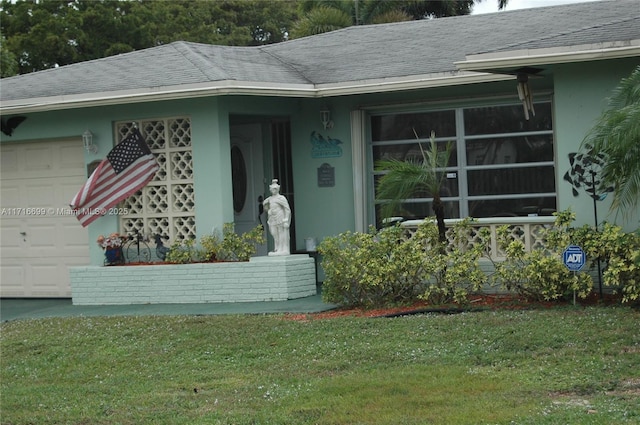 view of exterior entry with a garage and a lawn