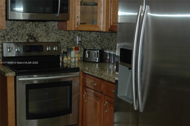 kitchen with stone countertops, appliances with stainless steel finishes, and tasteful backsplash