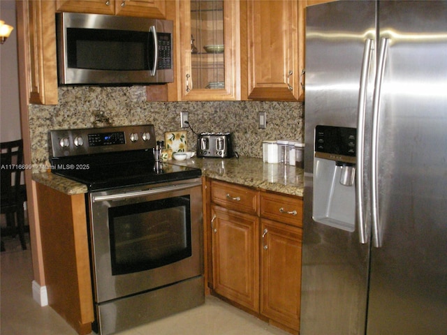 4723 NW 44th St, Tamarac, FL 33319 - kitchen featuring brown cabinets, stainless steel appliances, light stone counters, and backsplash