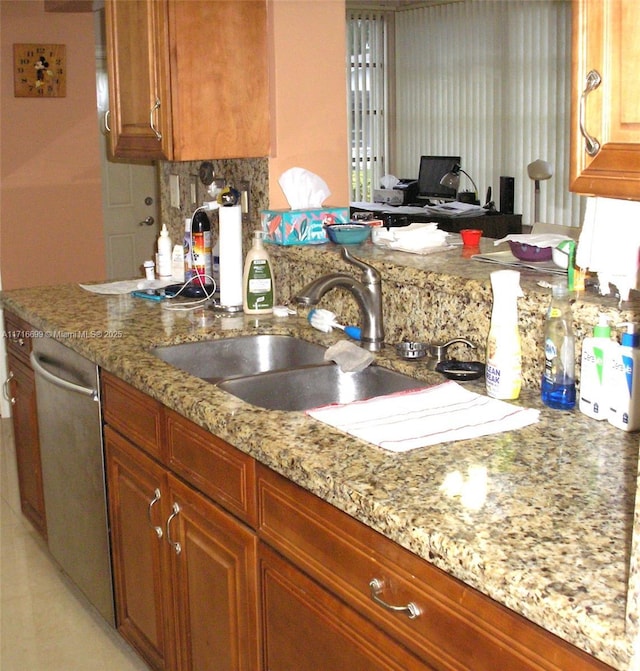 kitchen featuring backsplash, light stone counters, sink, and stainless steel dishwasher