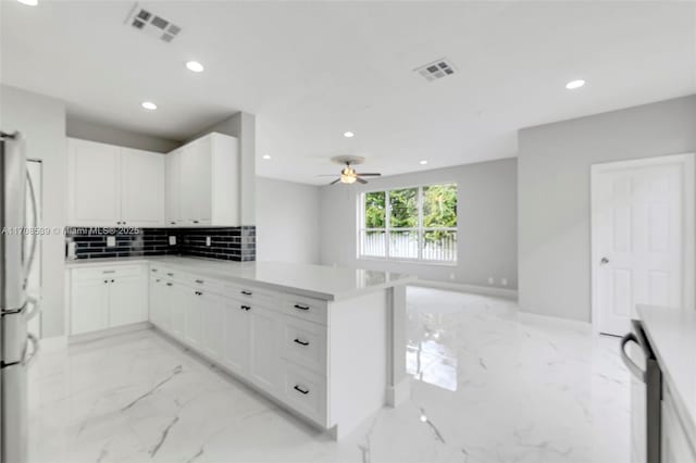 kitchen featuring ceiling fan, stainless steel appliances, kitchen peninsula, decorative backsplash, and white cabinets