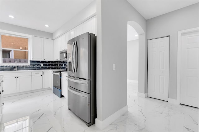 kitchen featuring decorative backsplash, sink, white cabinetry, and stainless steel appliances