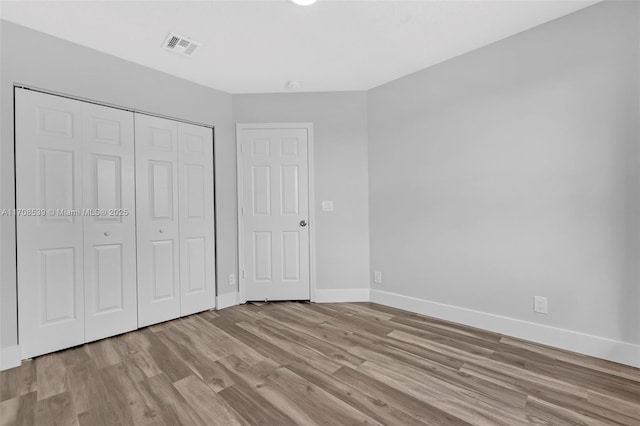 unfurnished bedroom featuring light hardwood / wood-style flooring and a closet