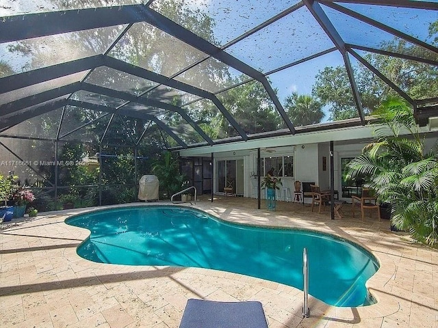 view of swimming pool with glass enclosure, ceiling fan, and a patio