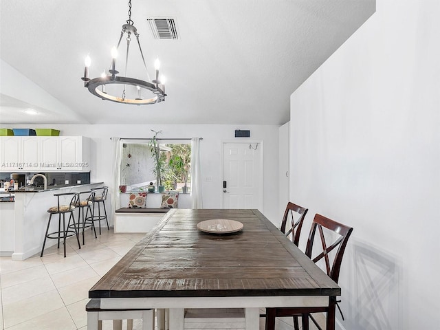 tiled dining area featuring sink, a chandelier, and lofted ceiling