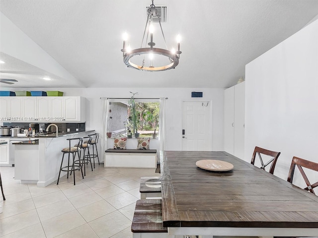 tiled dining area featuring lofted ceiling, sink, and a chandelier