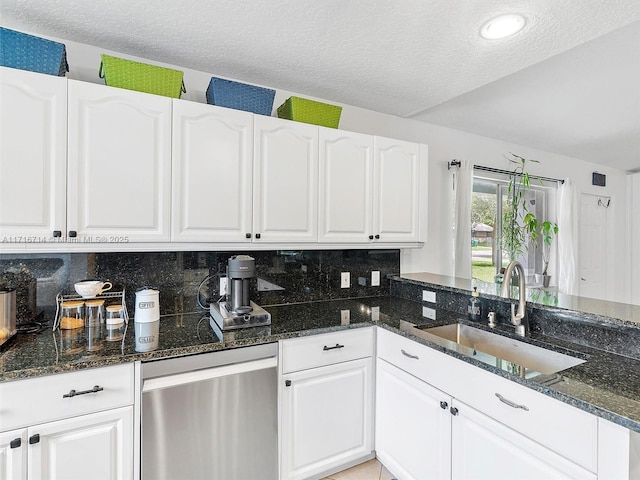 kitchen featuring dark stone countertops, sink, white cabinets, and a textured ceiling