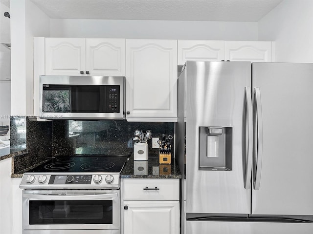 kitchen with decorative backsplash, a textured ceiling, stainless steel appliances, dark stone countertops, and white cabinetry