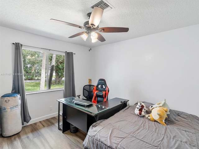 bedroom with ceiling fan, light hardwood / wood-style flooring, and a textured ceiling