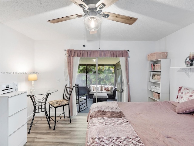 bedroom with ceiling fan, a textured ceiling, and light wood-type flooring