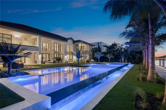 pool at dusk with a patio area and an outdoor living space