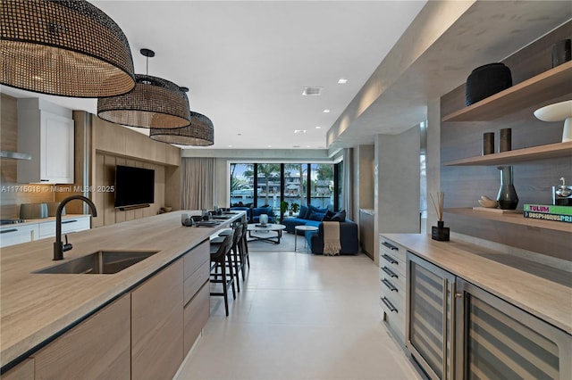 kitchen with sink, a wall of windows, hanging light fixtures, and beverage cooler