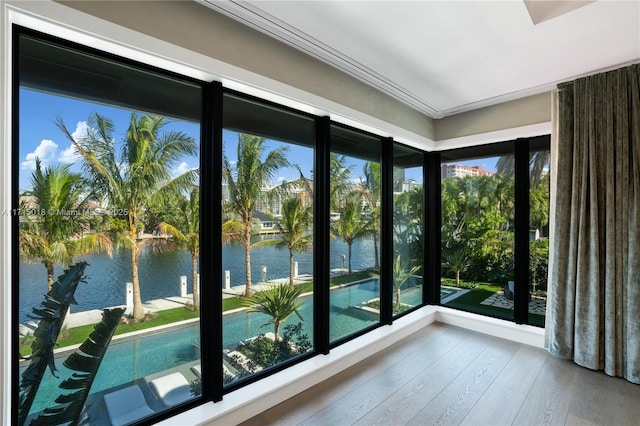 doorway with crown molding, a water view, and wood-type flooring