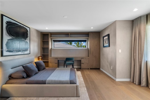 bedroom with built in desk and light hardwood / wood-style flooring