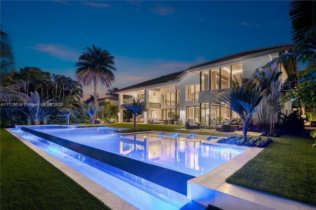 pool at dusk featuring a patio area and a yard