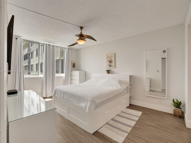 bedroom featuring ceiling fan, a textured ceiling, and hardwood / wood-style flooring