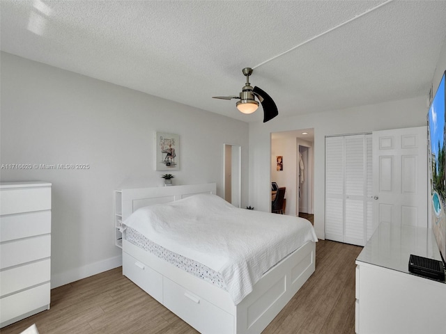 bedroom featuring ceiling fan, light wood-type flooring, a textured ceiling, and a closet