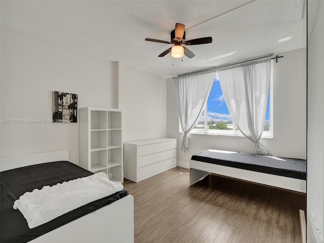 bedroom with light wood-type flooring, a textured ceiling, and ceiling fan