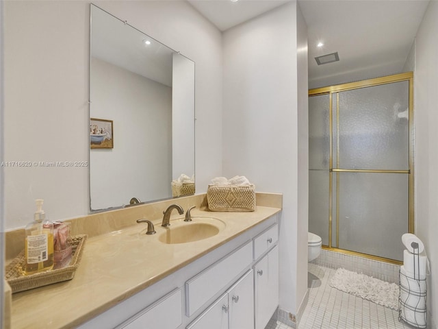 bathroom featuring tile patterned floors, vanity, a shower with shower door, and toilet